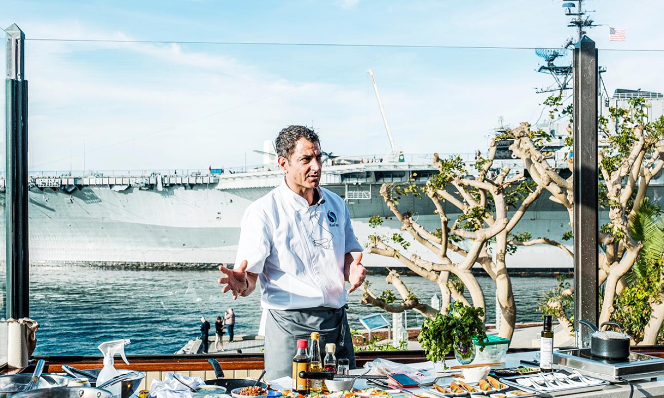 Chef stands by a harbor with yellowtail dishes