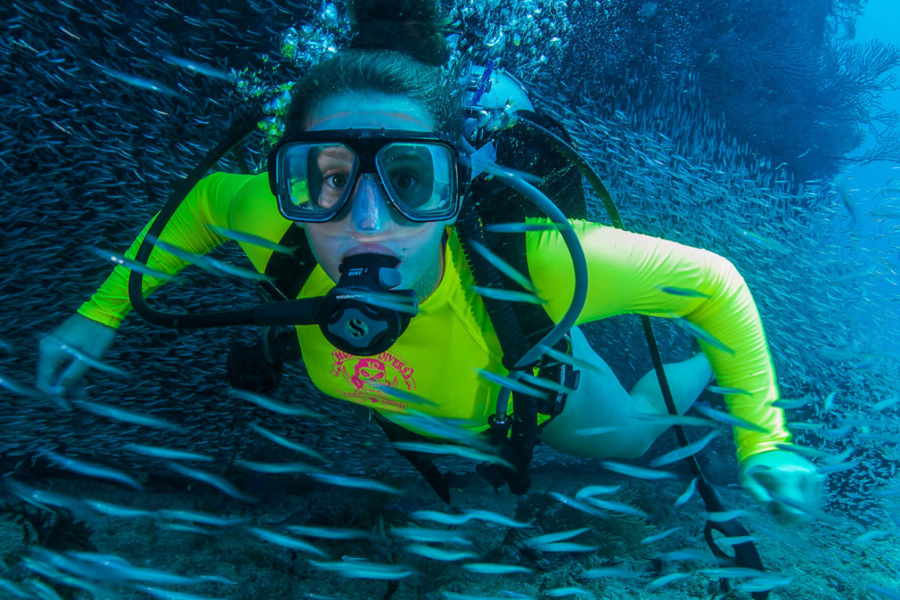 Young female scuba diver swimming with fish
