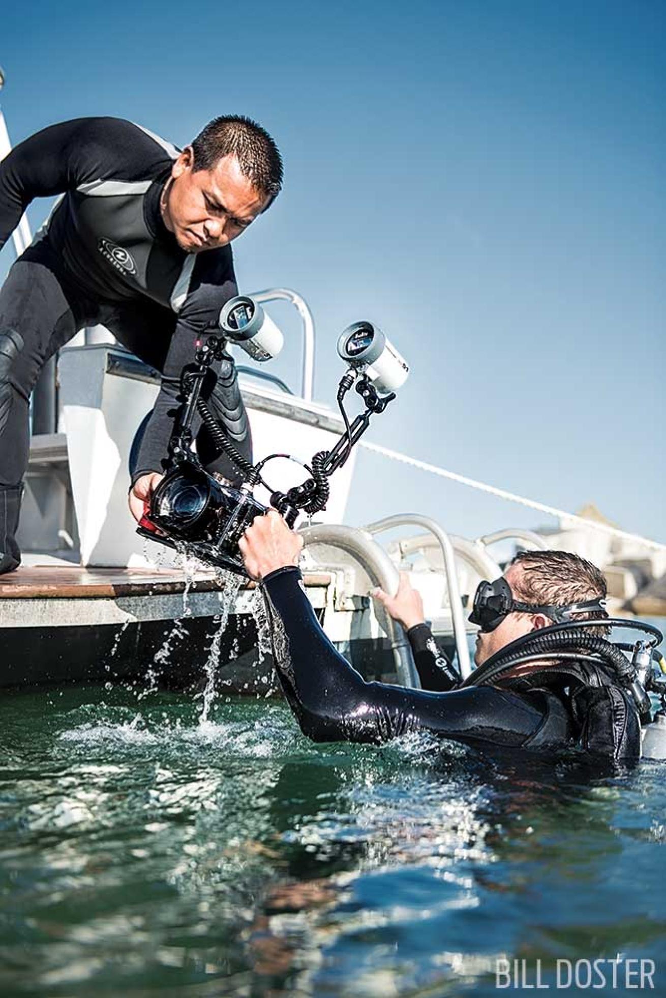 Divers with underwater cameras getting into boat