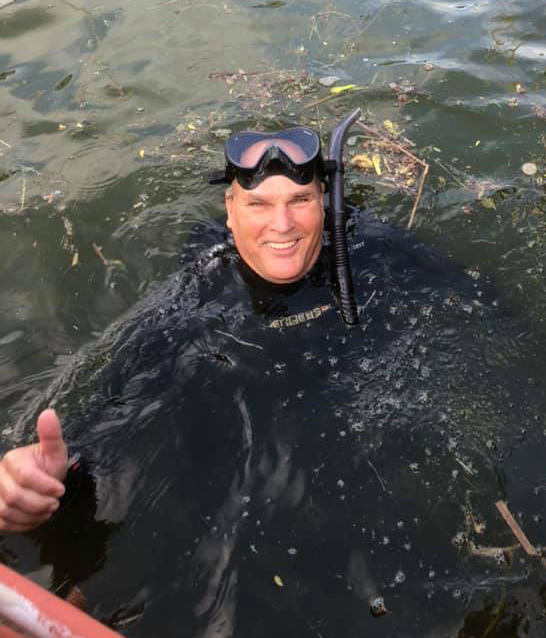 Robert Gratton gives a thumbs up from the water while wearing a wetsuit
