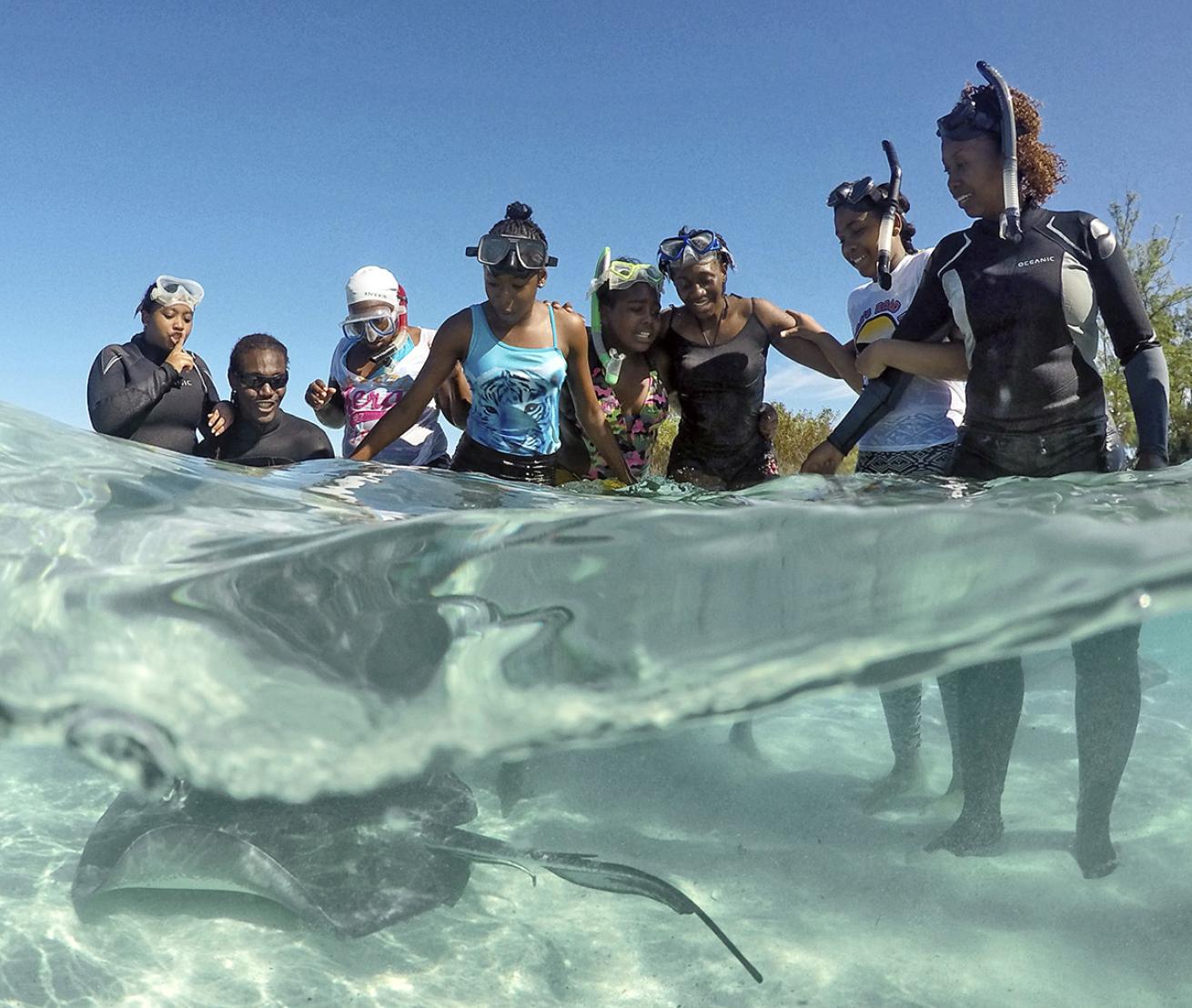 Bahamian children gather around a sting ray.