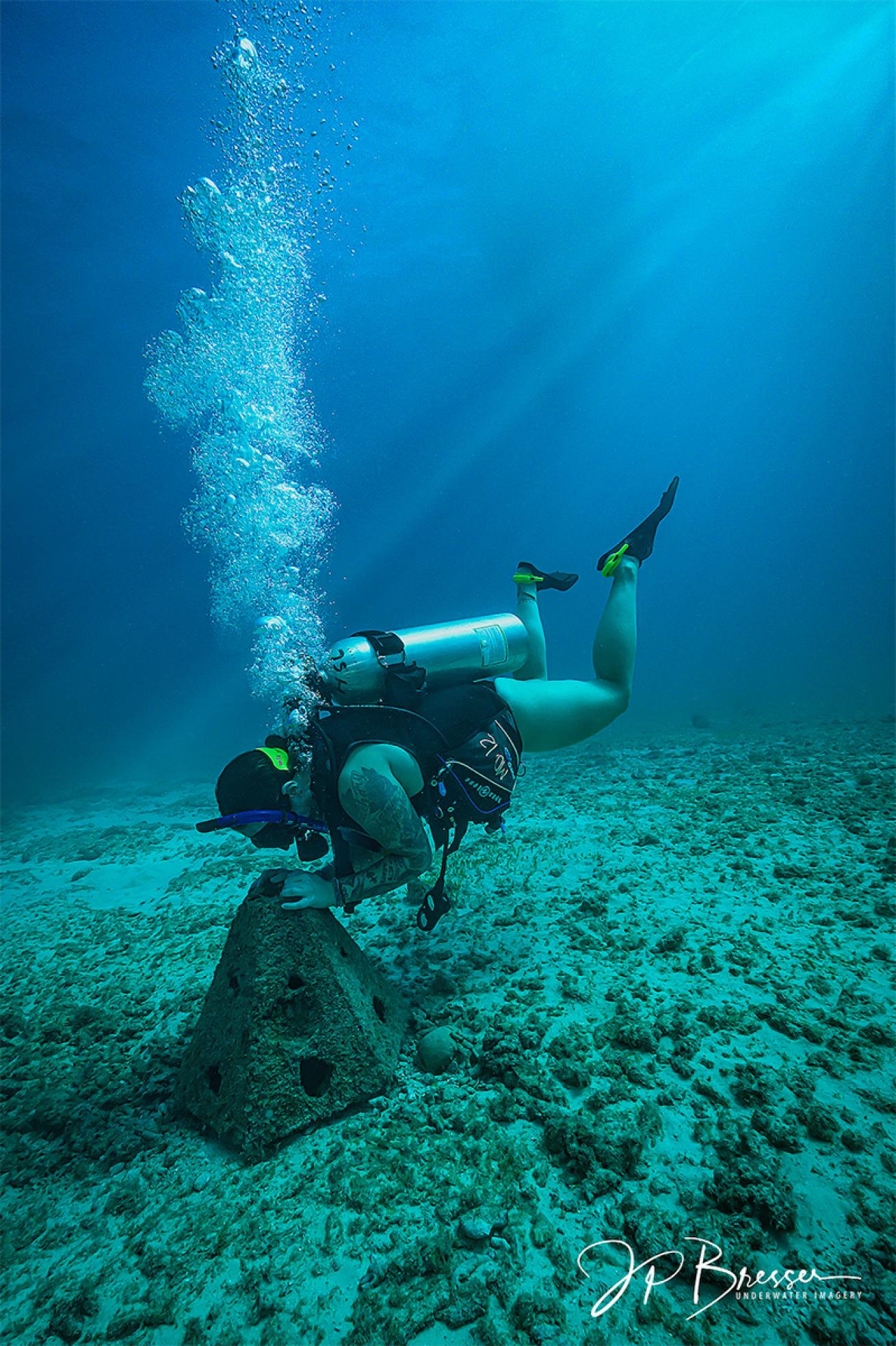 Ashley Bugge touches the artificial reef in which her husband's remains are mixed.