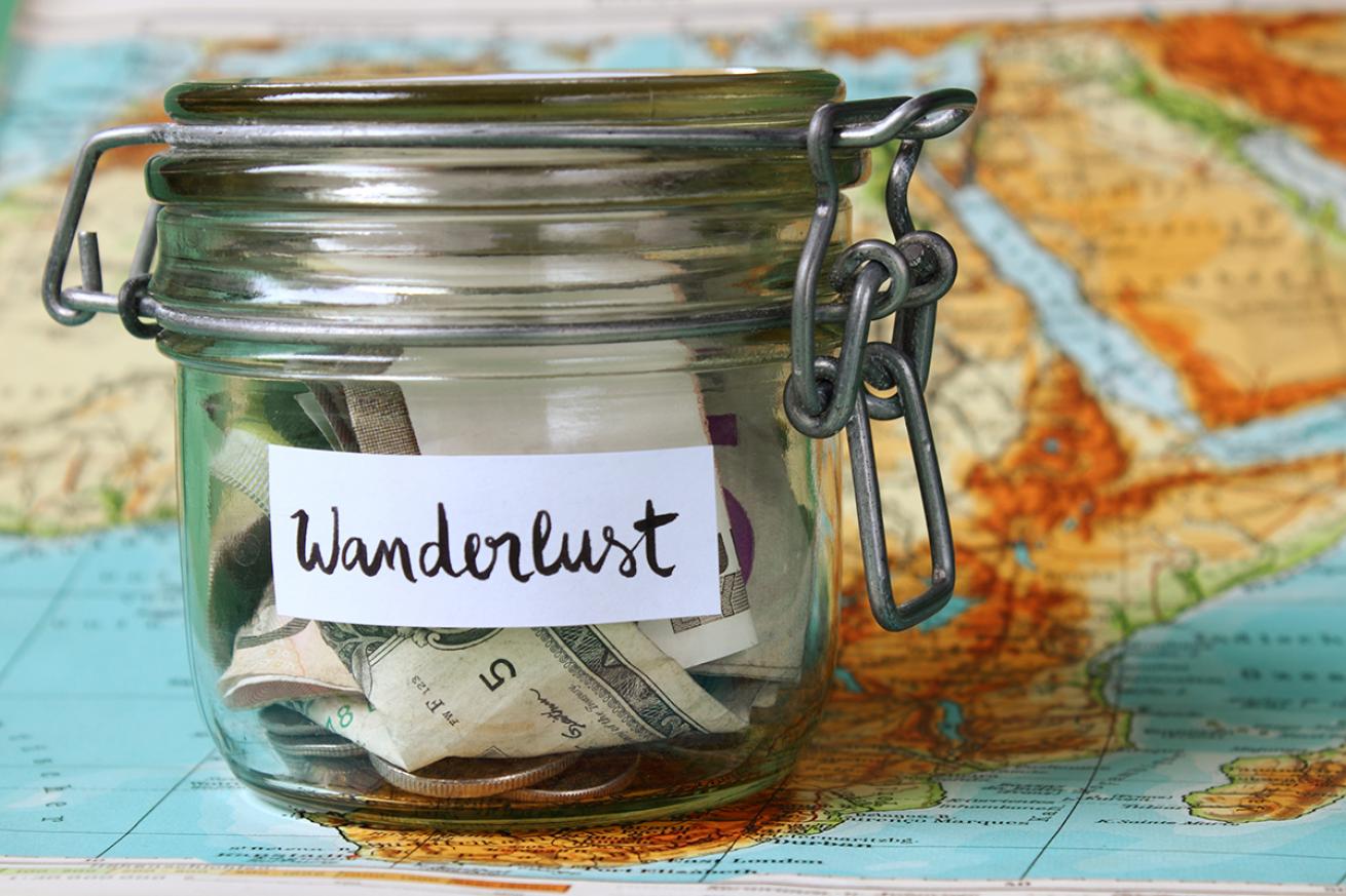 Jar of cash labelled "Wanderlust" sits on a world map