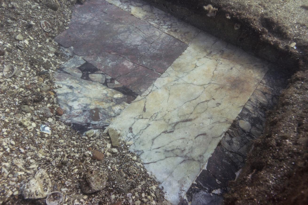 A small section of a tiled floor sticks out from underneath dislodged sand.