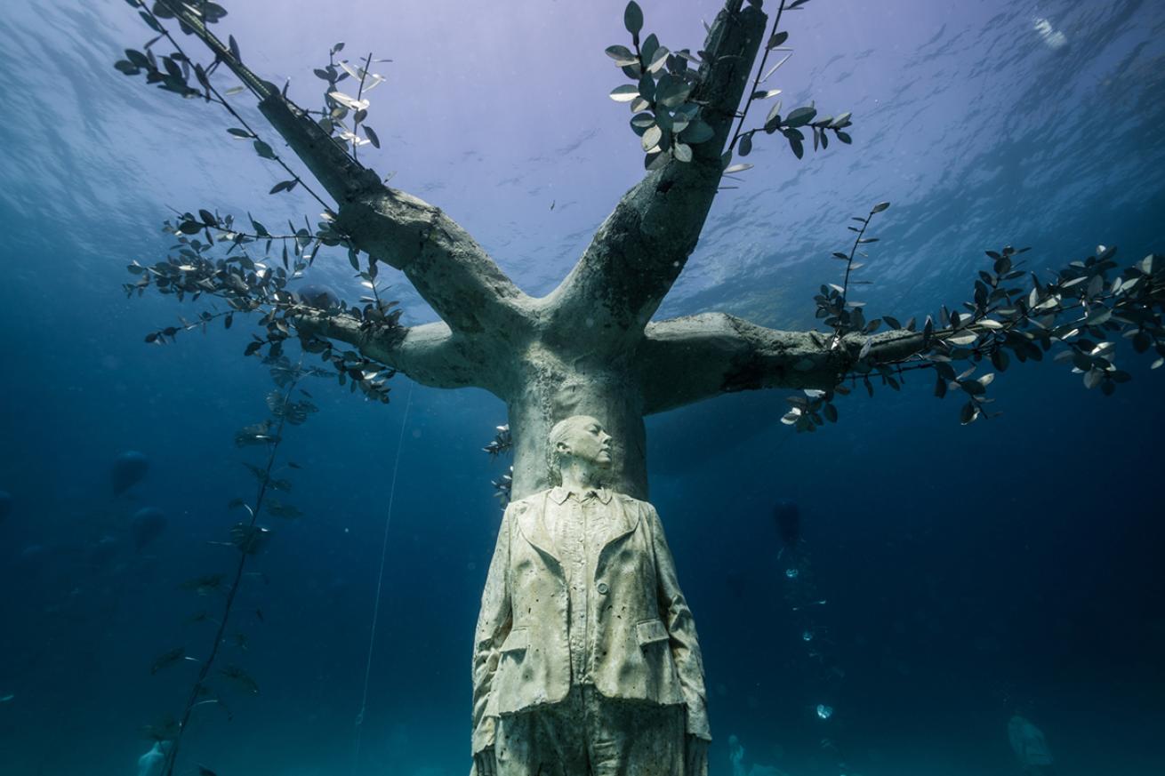 Underwater sculpture of man standing against a tree