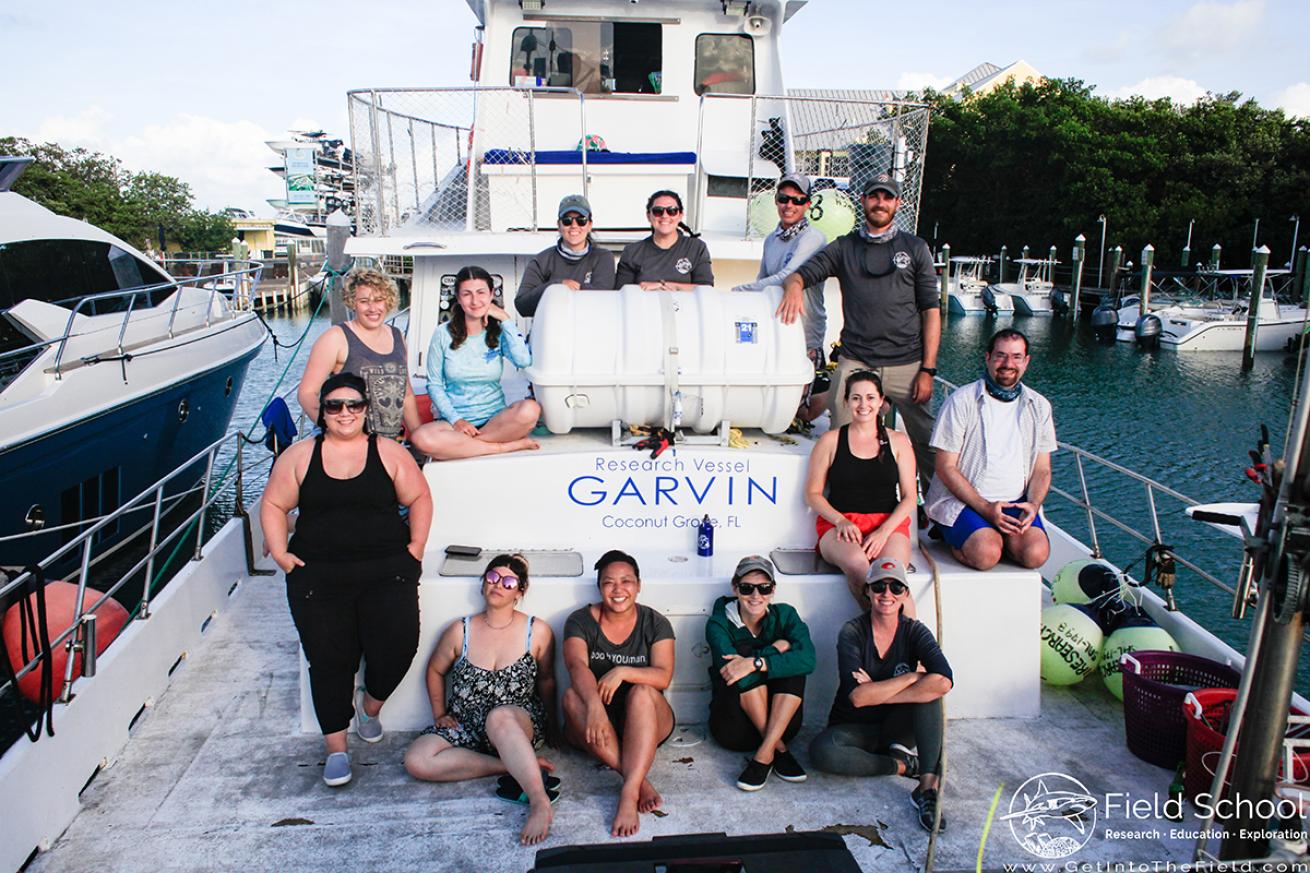 Thirteen people gather on the deck of a boat