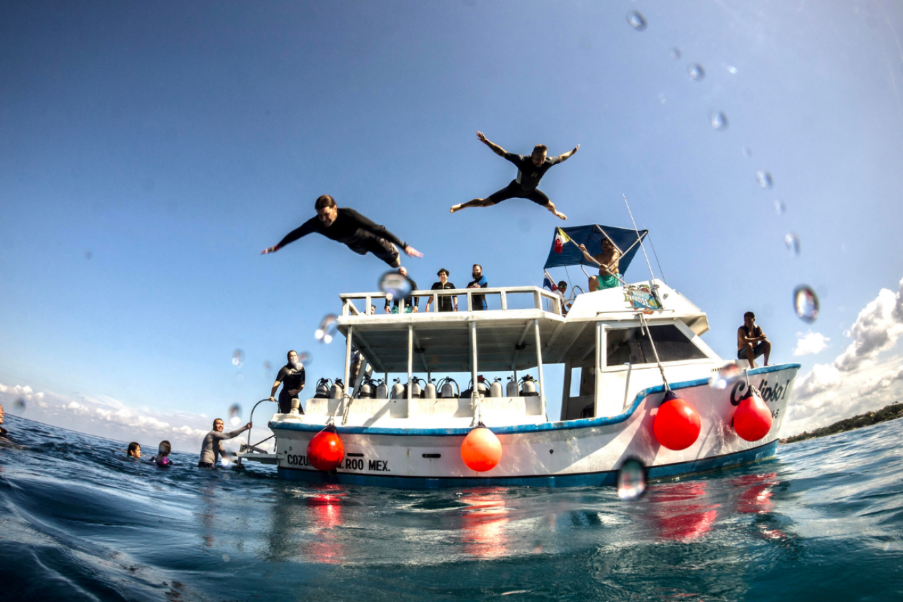 Two people jumping off a boat