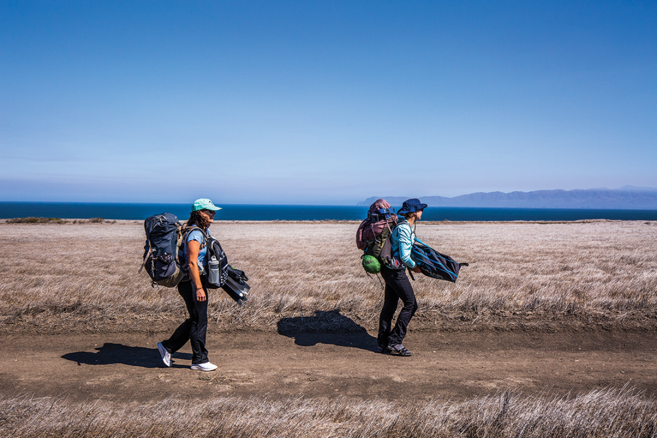 Backpackers hiking with dive gear