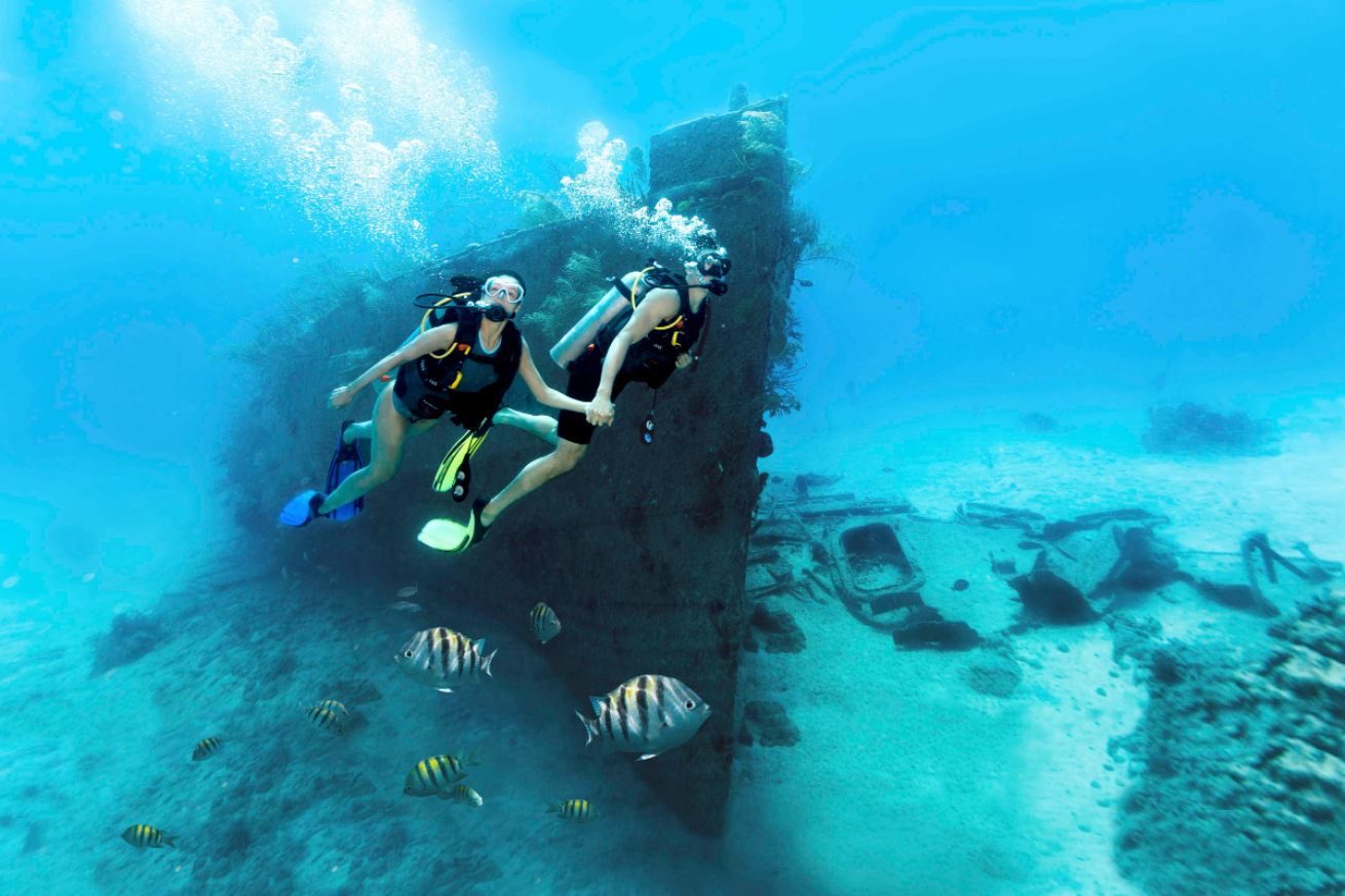 A couple holding hands in scuba gear underwater