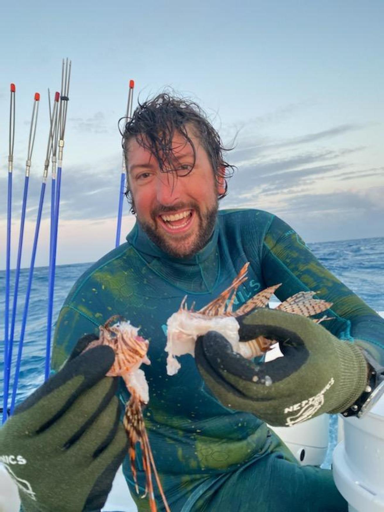 Diver in boat holding lionfish