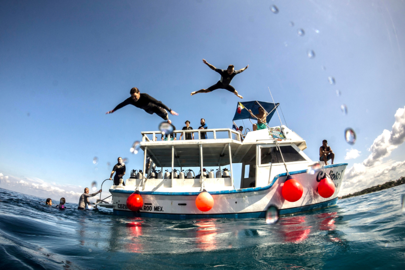 People jumping off boat into the ocean