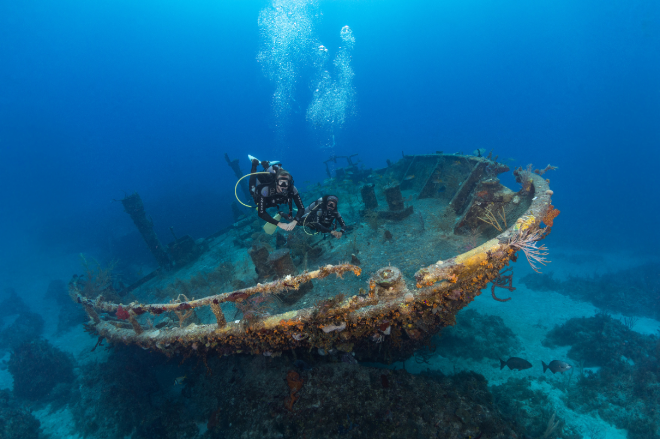 Two divers swimming over wreck