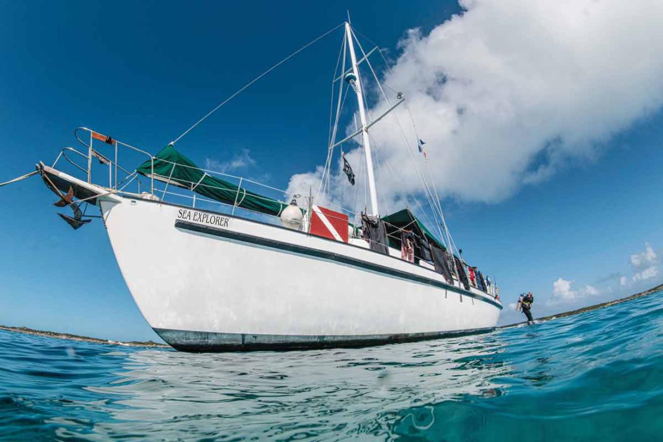 a boat sailing over water with a diver jumping off the back