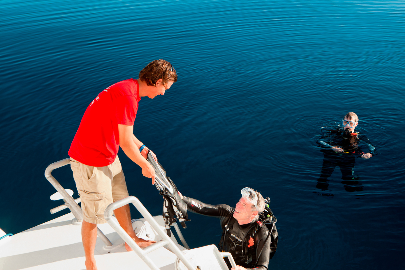 A person in a scuba suit and scuba diver on a boat
