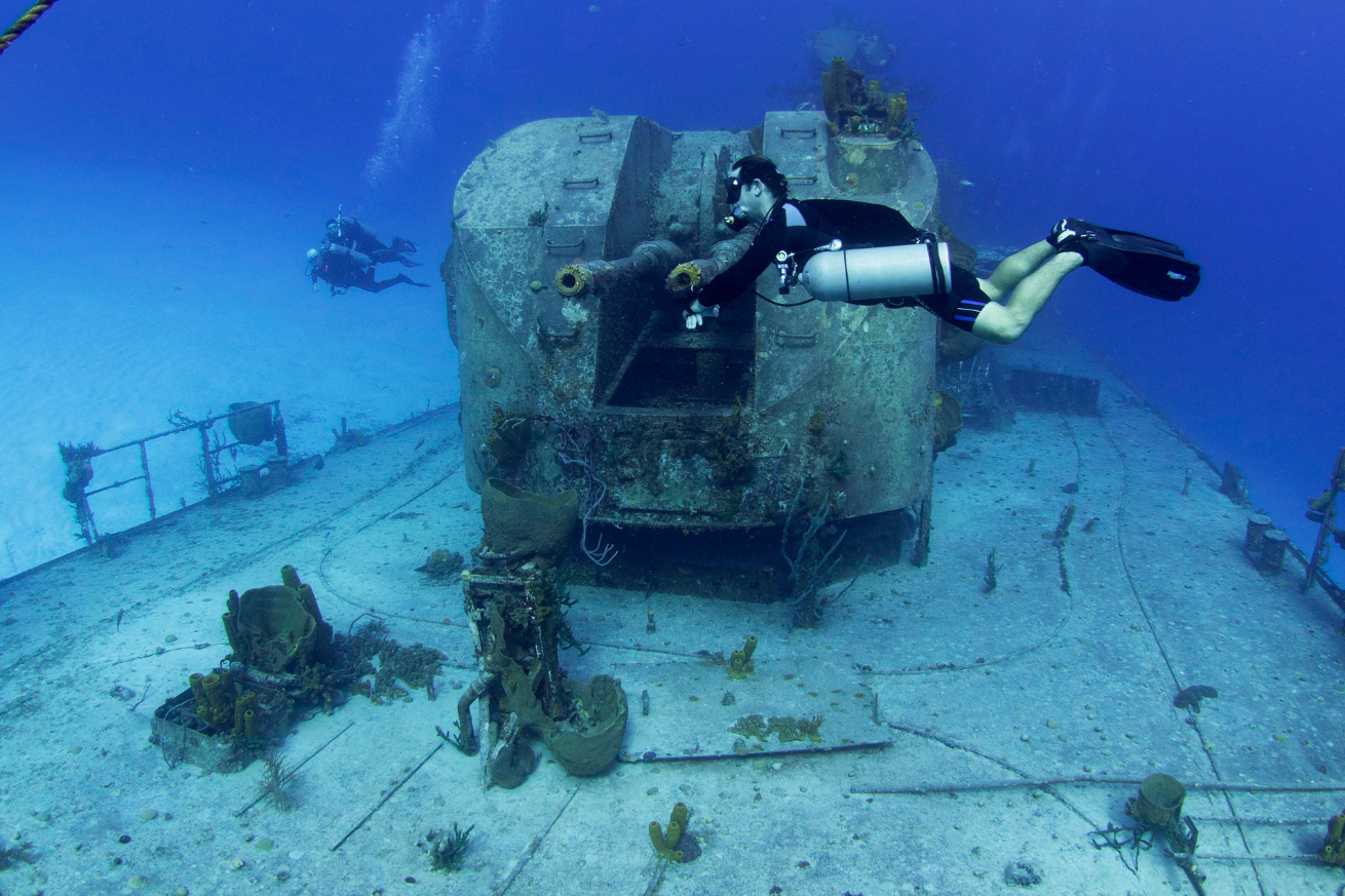 A diver in scuba gear underwater diving a wreck