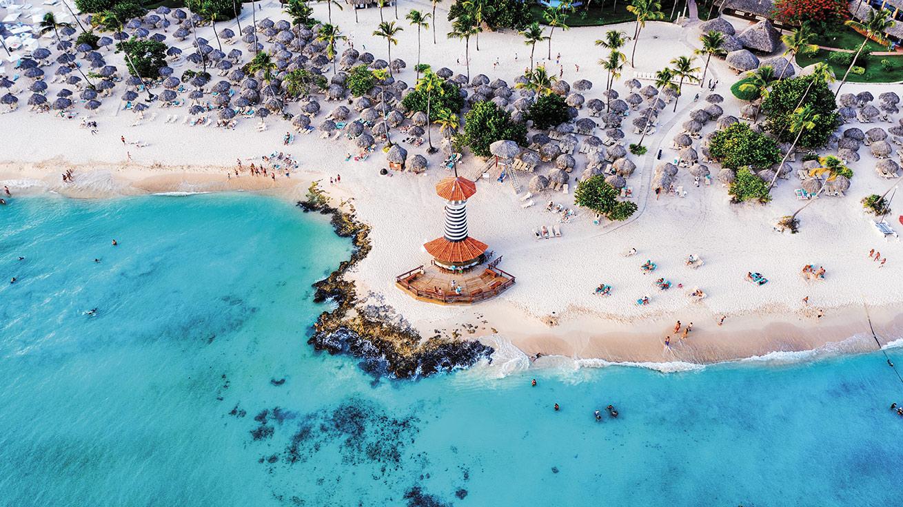 drone shot of clear waters and white sand of Bayahibe featuring a lighthouse 