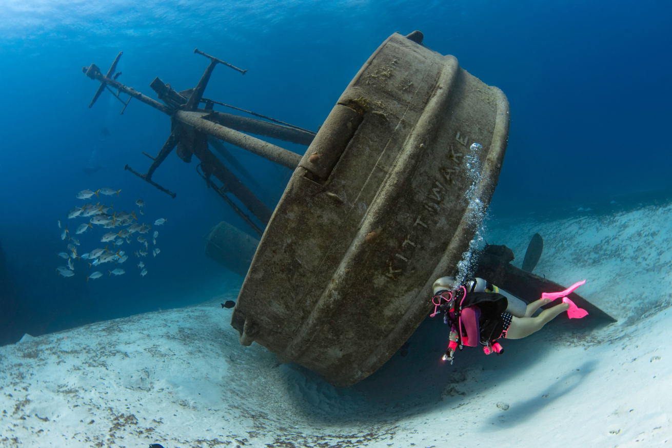 A diver in scuba gear underwater next to a wreck