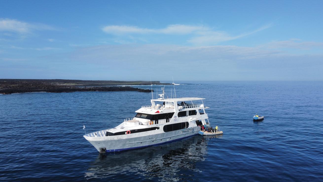 A boat in the water with two tenders