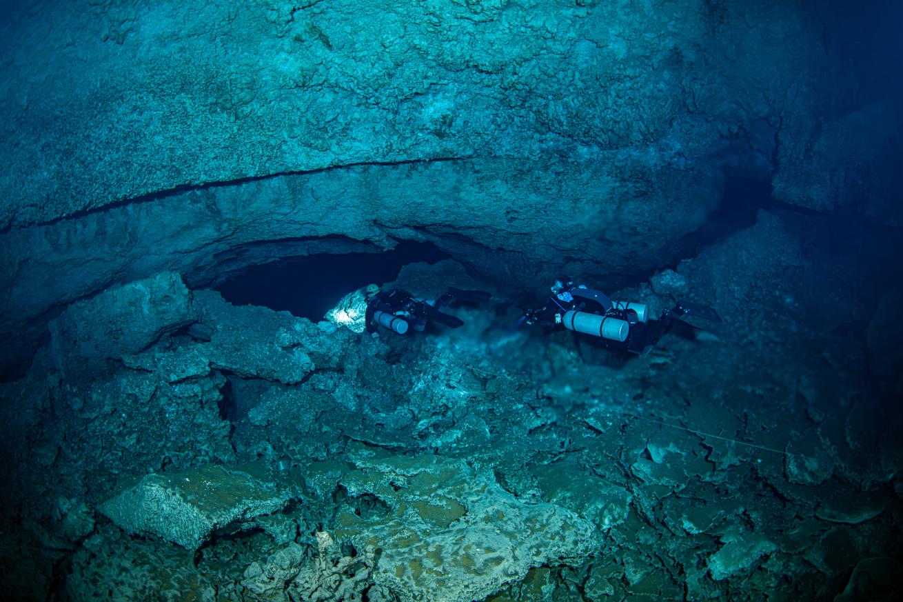 Two cave divers pass through the distorting halocline to enter a cave on Grand Bahama.