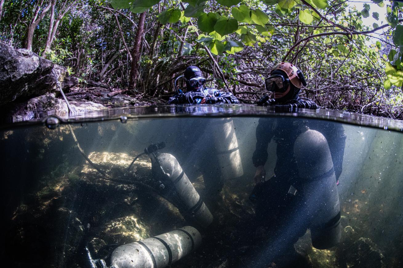 The author (left) and Zenato don their gear in a shallow pool outside the entrance to the cave.