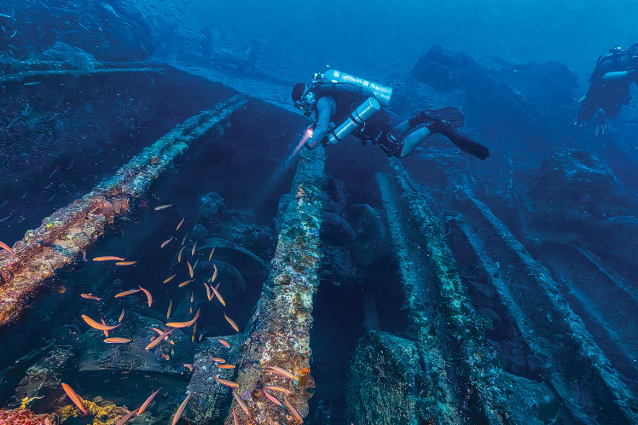 a diver inspects a wreck in Chuuk Lagoon